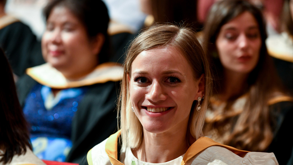 A student at an RCM graduation ceremony smiling at the camera
